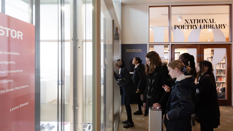 Group of school students stood outside the National Poetry Library looking at a glass lift