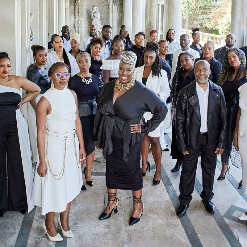 The 30 or so singers of the Kingdom Choir stand on a portico, all dressed up in black and white clothes