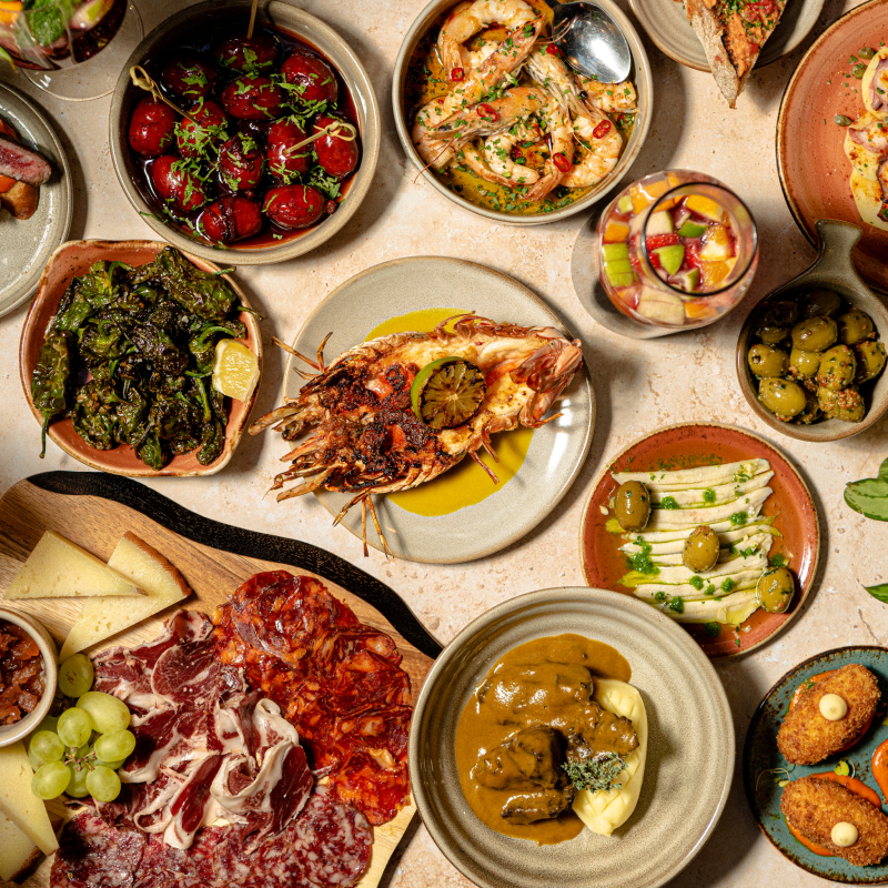An overhead shot of tapas dishes from cooked fish to charcuterie boards and appetizers.
