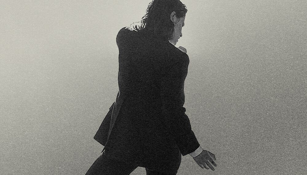 Musician, Christine and The Queens pictured in black and white from the back in a suite