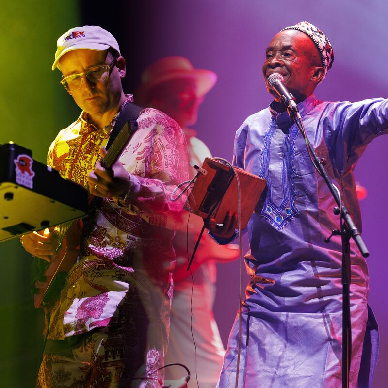 A composite image from Hot Congotronics performance at Grace Jones Meltdown that feature four members of the band, including Hot Chip's keyboardist a white man who wears a white baseball hat, a vocalist from Kasai Allstars, a black man who wears a long sleeve Dashiki, and in the background two male guitarists, each white men wearing wide brimmed hats are just visible but out of focus