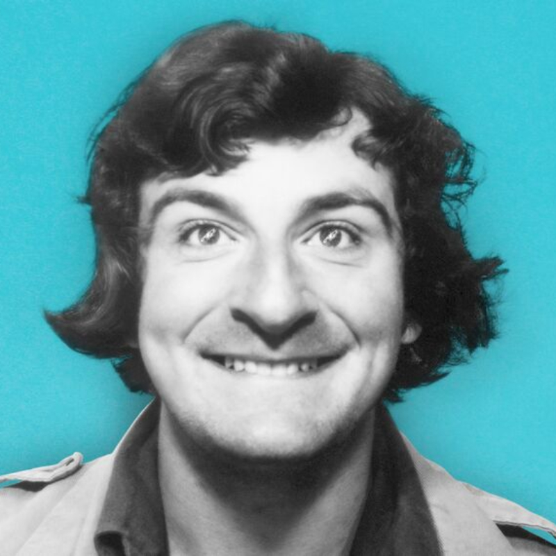 Douglas Adams smiling in front of a bright blue background