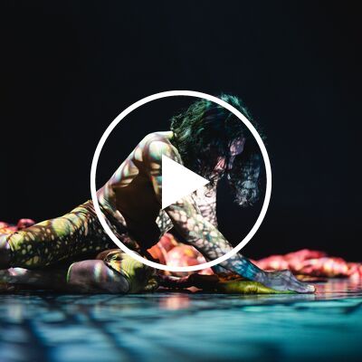 A performer shaded by the light of a colourful projection