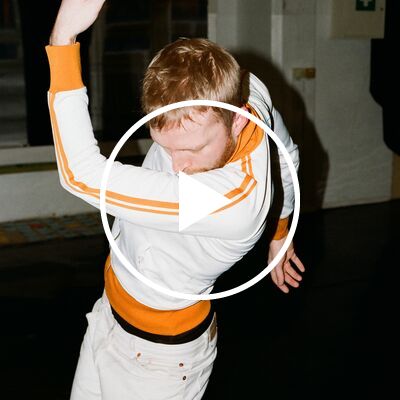 A man dressed in white and orange dancing