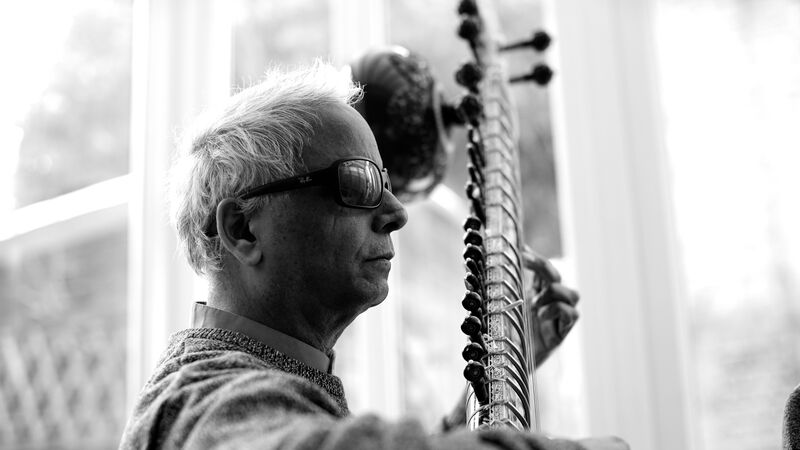 A black and white photo of the artist, Baluji Shrivastav, playing the sitar.