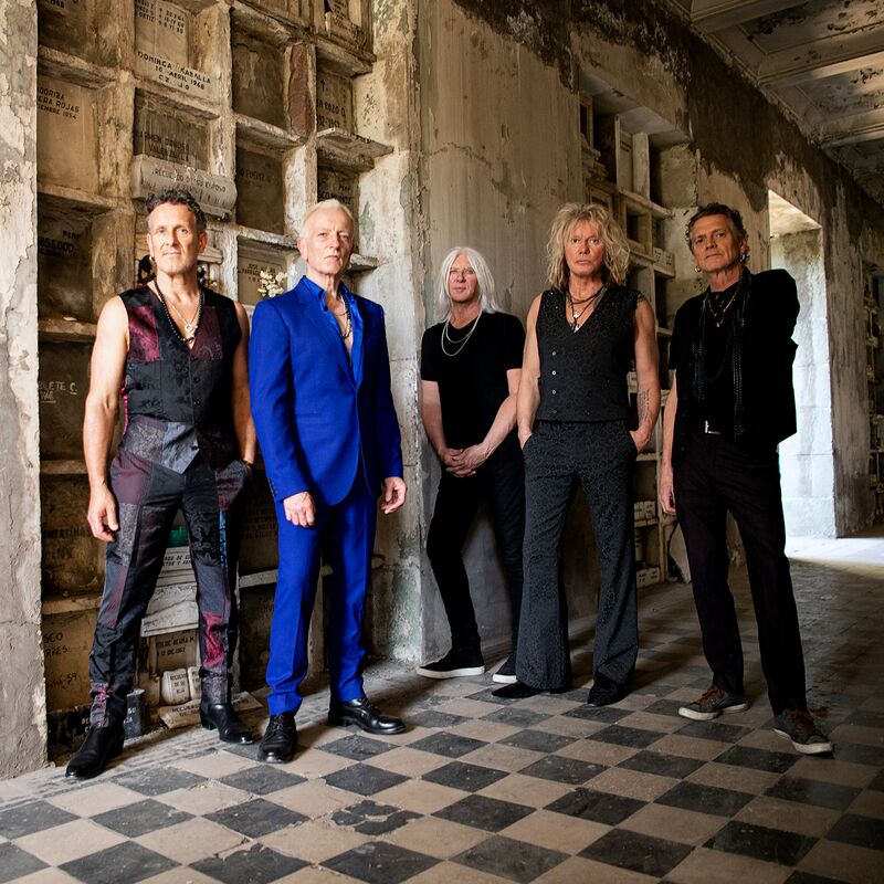 The 5 members of Def Leppard pose in a once grand but now dilapidated corridor