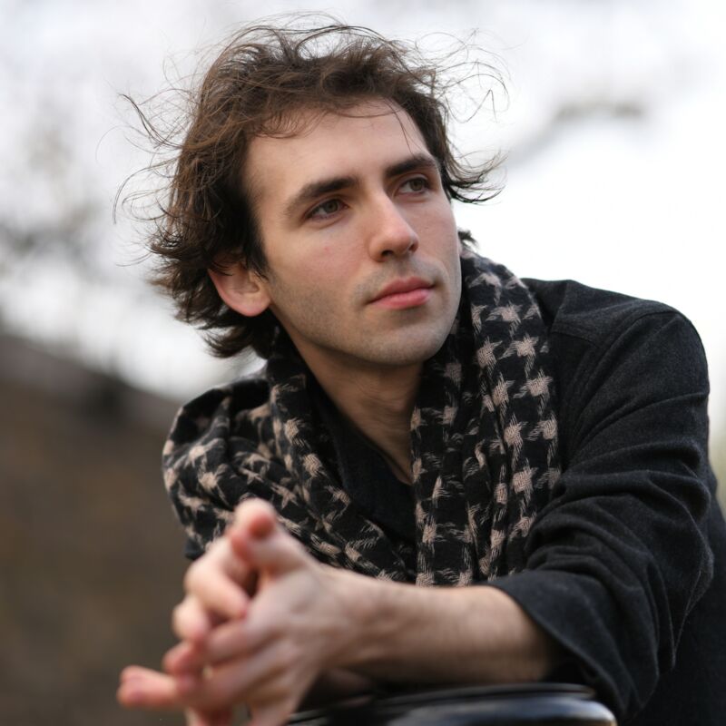 Alexandre Kantorow wearing a houndstooth scarf and staring into the distance