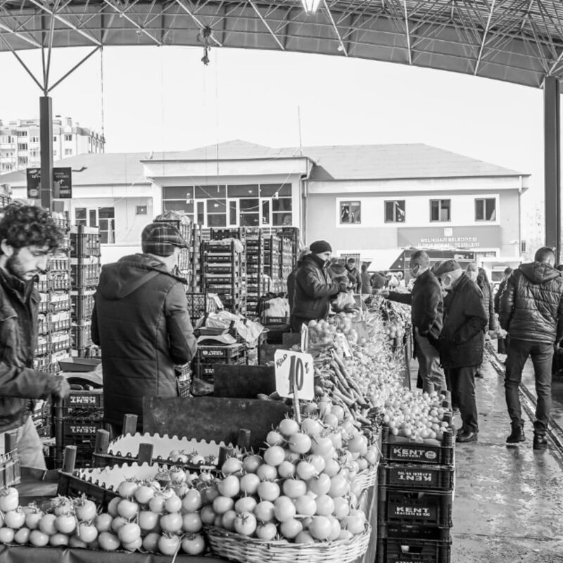 Black and white photograph of a covered market selling vegetables.