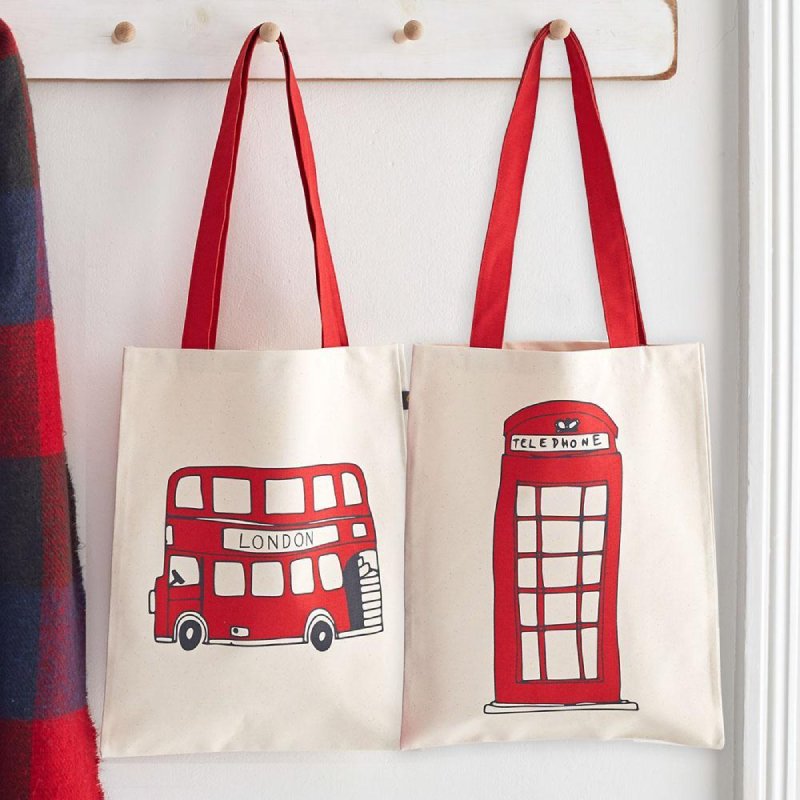 A hanger with two white and red tote bags next to each other, showing both sides of the Telephone Box and London Bus reversible bag.