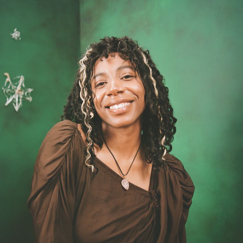 Dominque Palmer, a young woman, smiling against a green background 