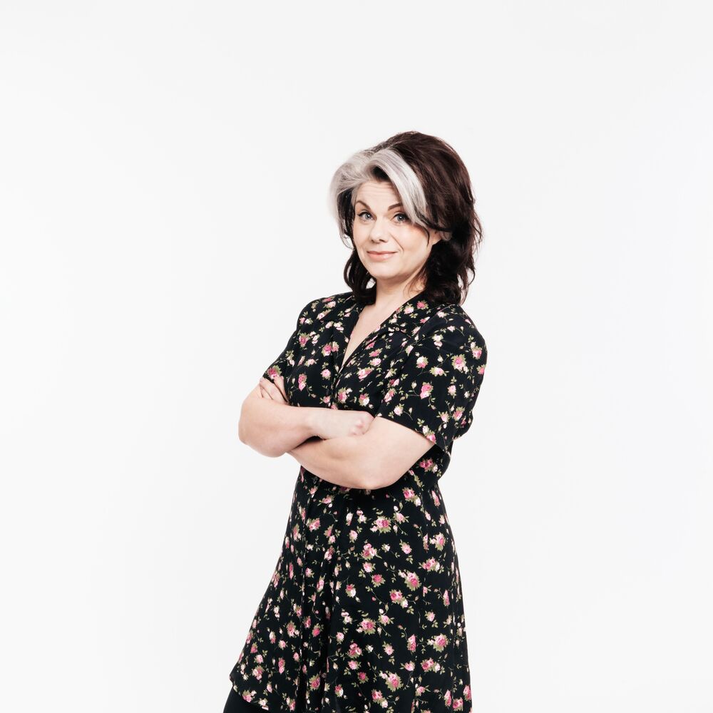 Caitlin Moran wearing a flowery dress with her arms crossed