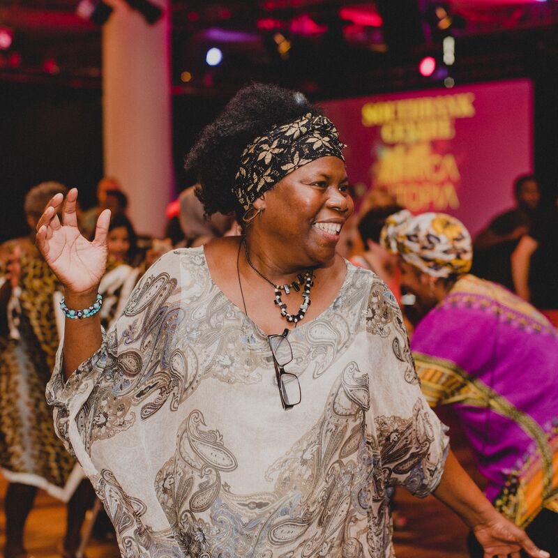 A smiling black woman dancing in The Clore Ballroom