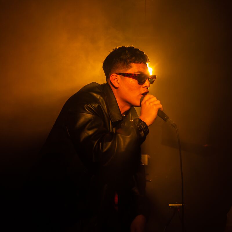 A singer wearing sunglasses, holding a mic to his mouth