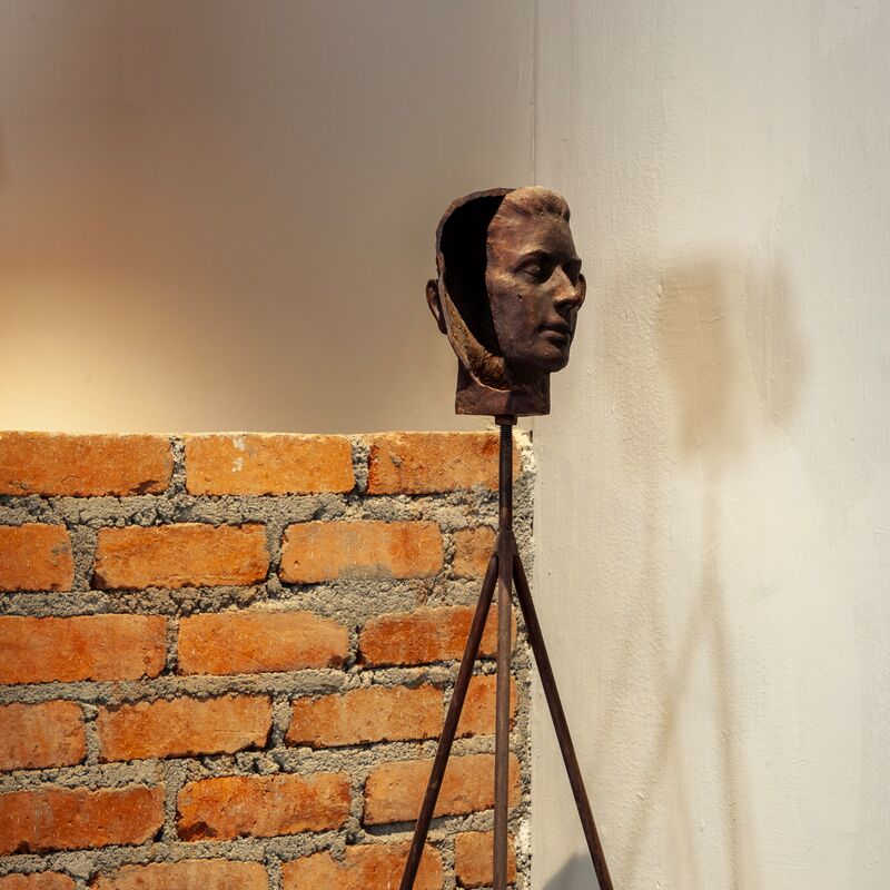 A metal tripod with metal face casts at the top
