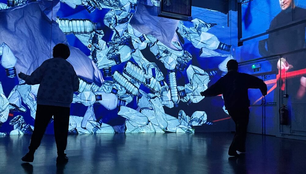 Two people in front of a projection of plastic water bottles
