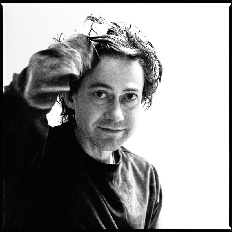 Black and white headshot of author Adam Thirlwell running a hand through his hair
