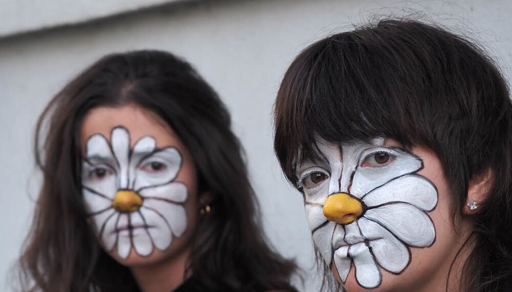 Two peope with white daisies painted on their faces