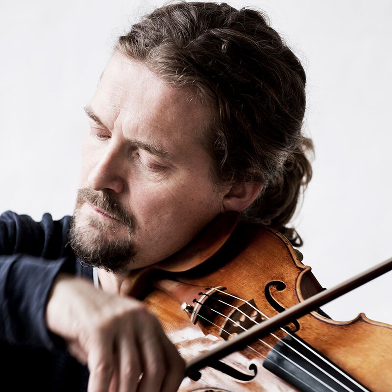 Violinist Christian Tetzlaff pictured with a violin by a white backdrop