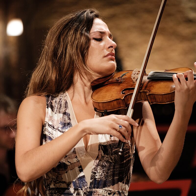 Violinist Nicola Benedetti playing the violin, wearing a black and white sleeveless dress