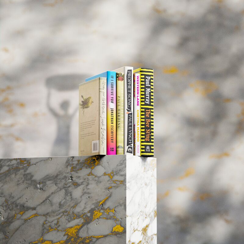 The six Booker Prize Shortlist books lined up on a marble plinth with gold flecks