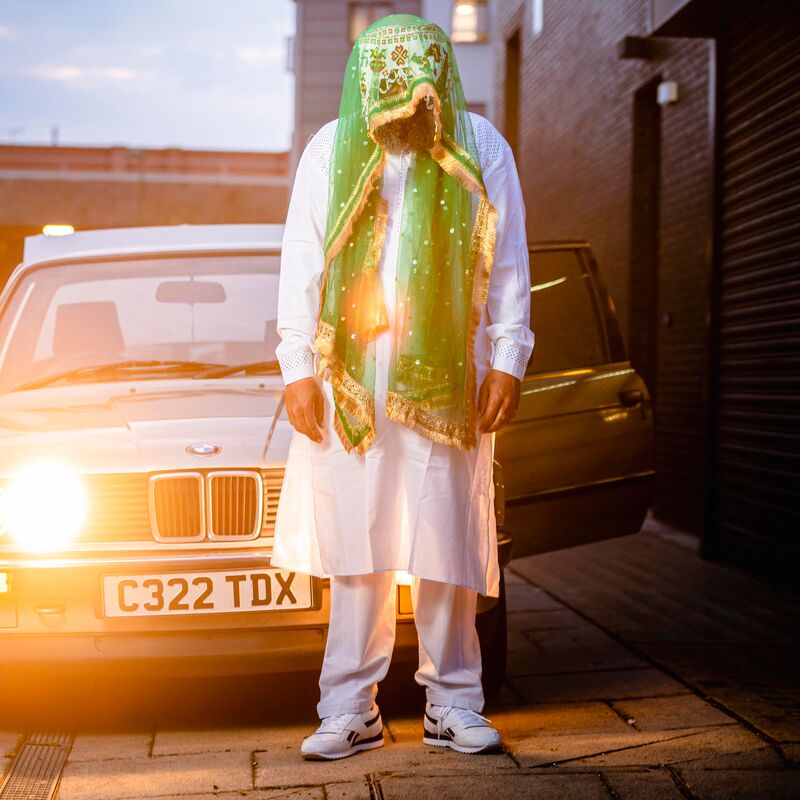 Dipesh Pandya standing in front of a car wearing a green veil