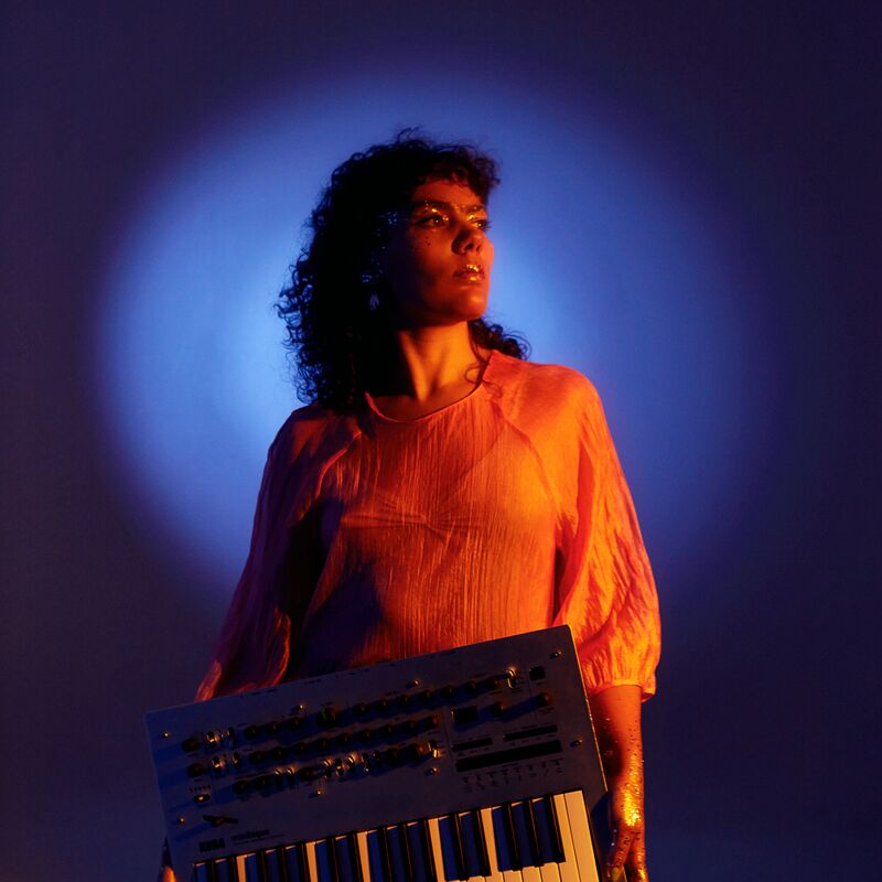 A woman holding a keyboard staring into the distance