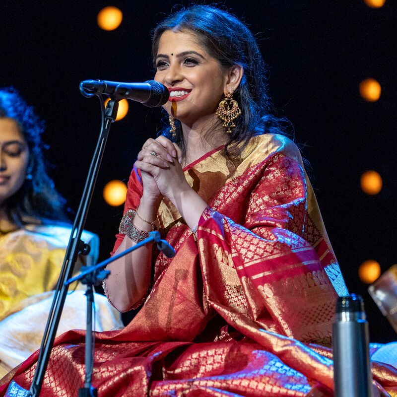 Kaushiki Chakraborty wearing a red sari sitting in front of a microphone.