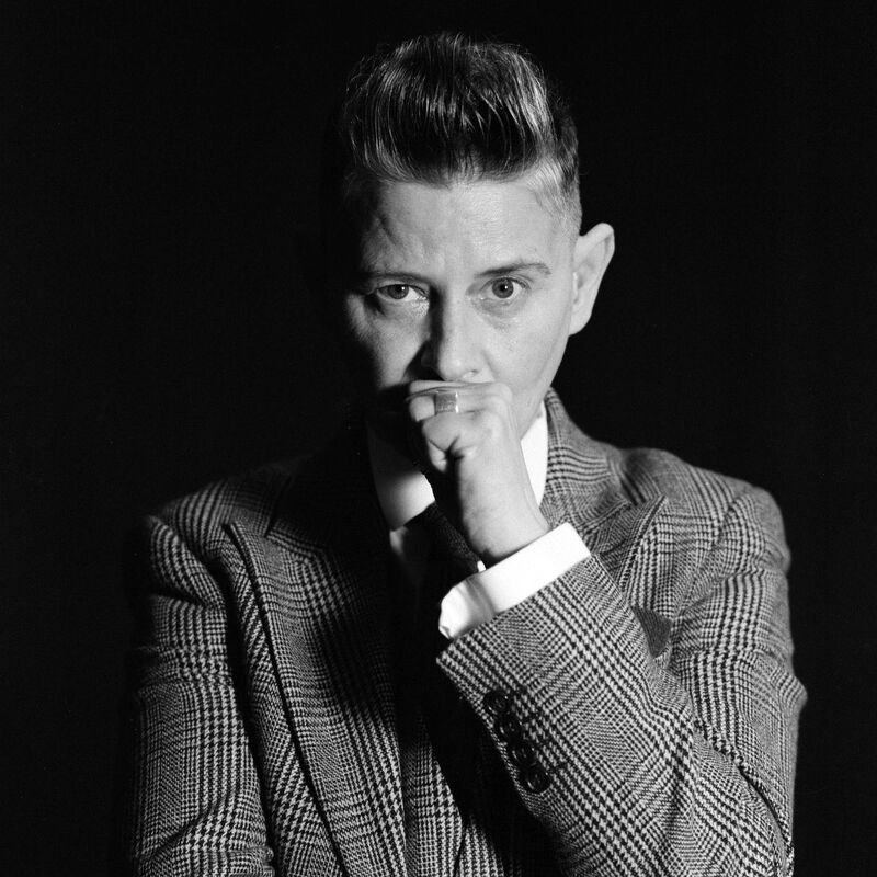 Black and white photo of author Joelle Taylor looking at the camera wearing a checked suit