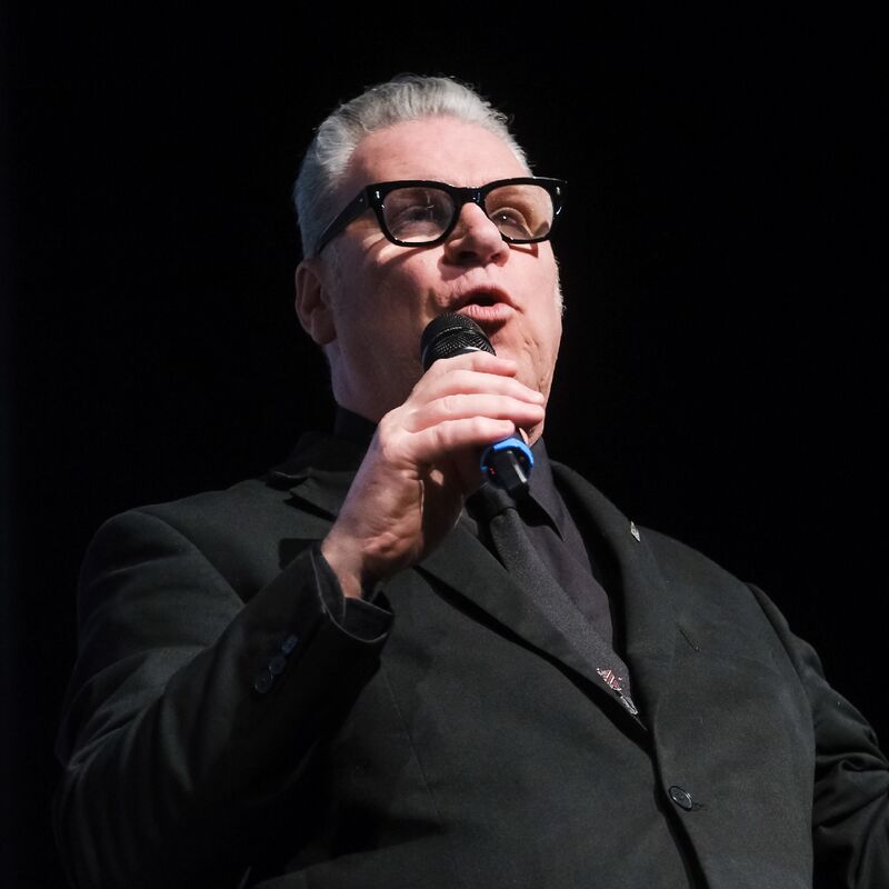 Mark Kermode, a man wearing glasses and a suit, speaking into a microphone