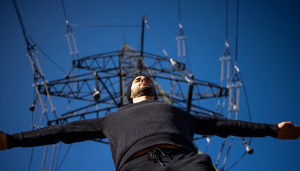 Looking up at multi instrumentalist Manu Delago under an electricity pylon.