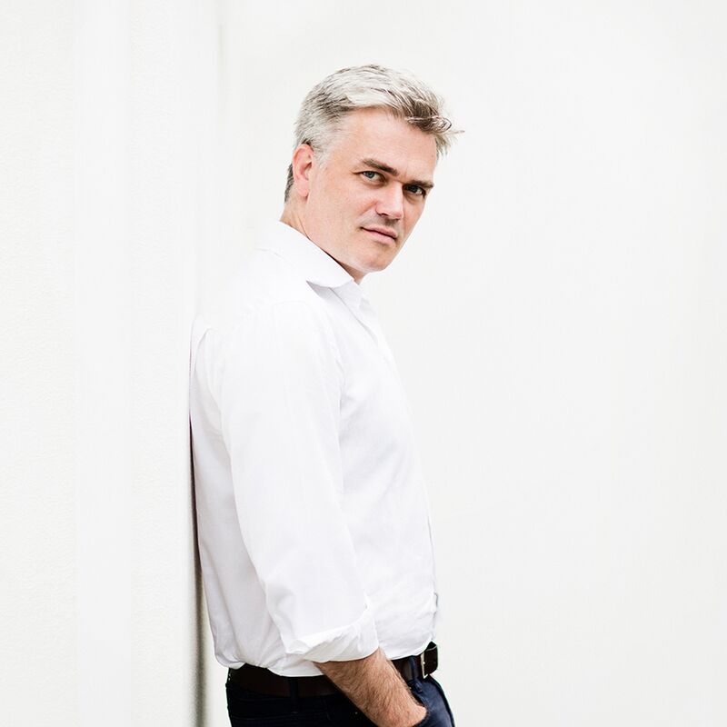Conductor Edward Gardner in a white shirt standing against a white background