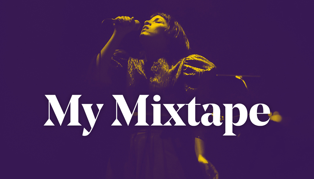 A woman with short dark hair is spotlit from above as she sings into a microphone against a dark background. The words 'My Mixtape' in white overlay the image