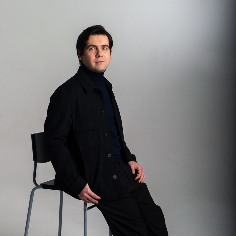 Vadym Kholodenko dressed in black casually sitting on a stool