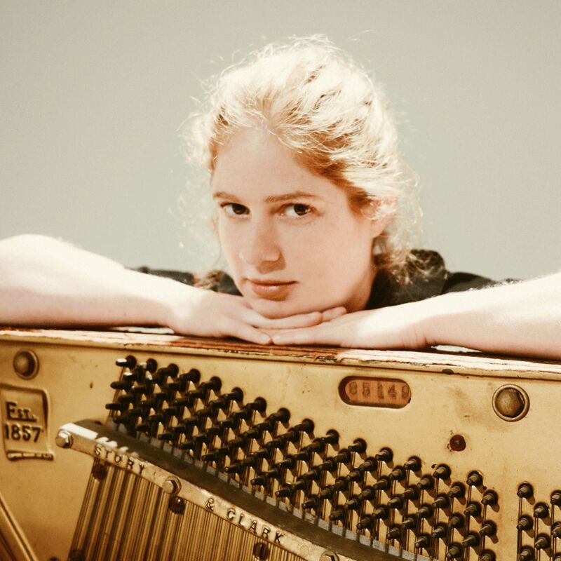 Maya Dunietz leans on a piano