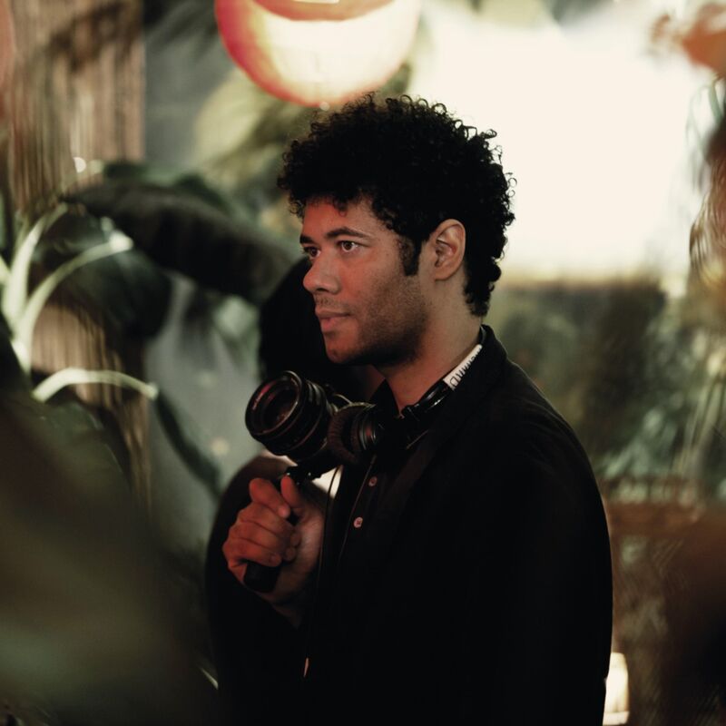 Richard Ayoade holding a camera in a jungle themed room