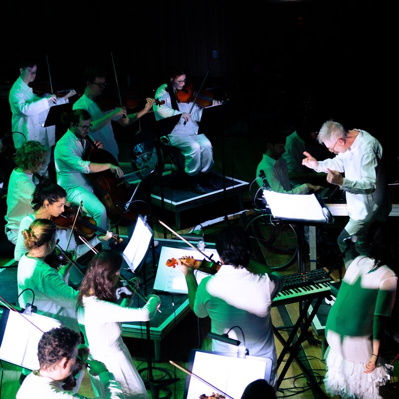 Paraorchestra: Trip the Light Fantastic at the Bristol Beacon. A view of the orchestra from above bathed in green light.