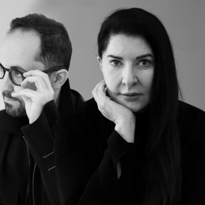 A black and white composite image of Igor Levit looking to the left of frame, wearing spectacles, and Marina Abramović looking directly at the camera