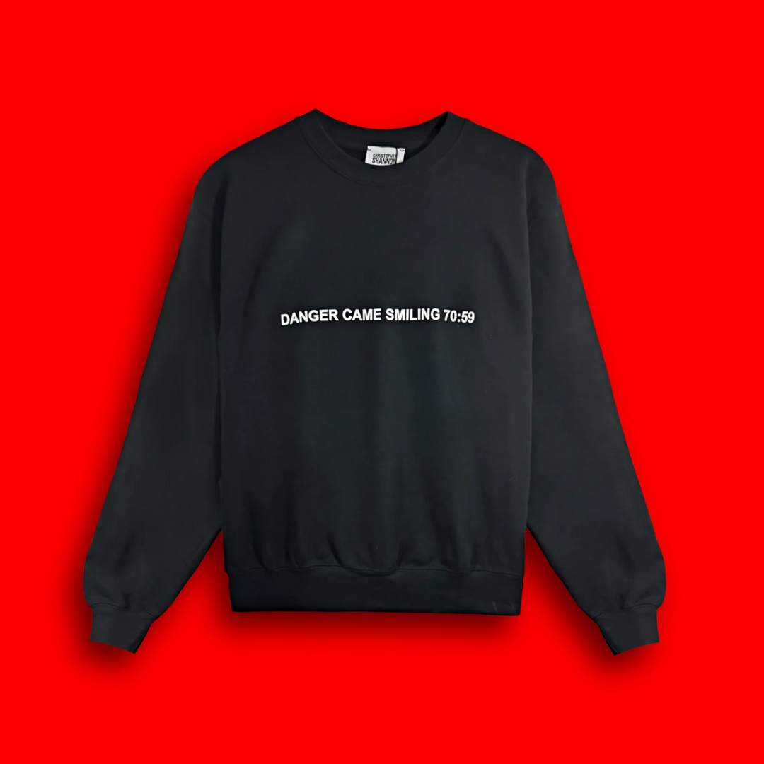 A photo of a black sweatshirt with Danger Came Smiling in white text on it.