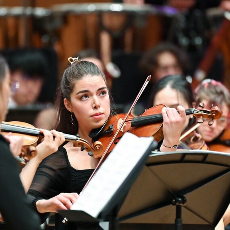 A woman playing the violin in an orchestra