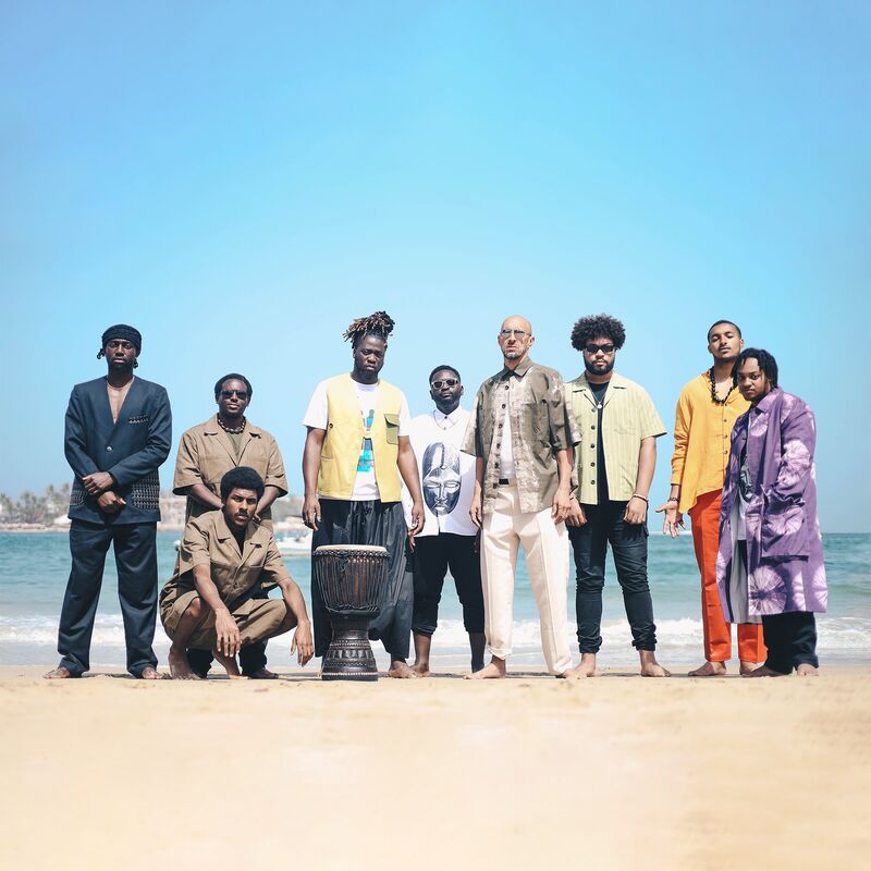 Members of the Balimaya Project standing on a beach with the ocean and blue skies behind them.