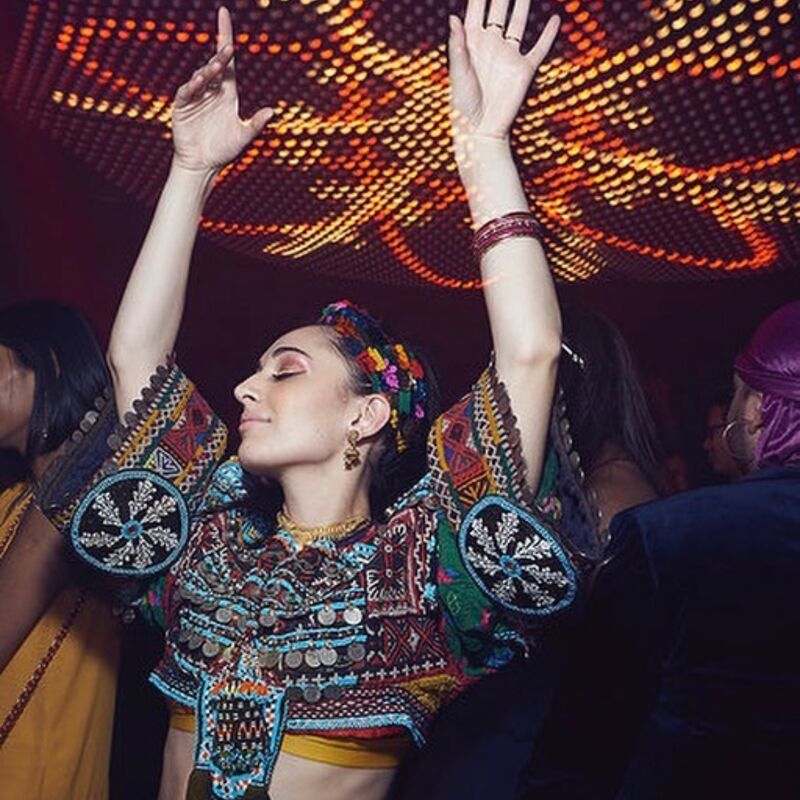 A dancer wearing an embroidered top with their hands in the air