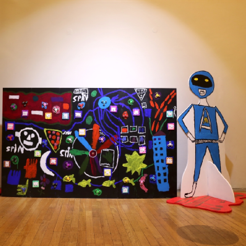 A cardboard alien next to a mural