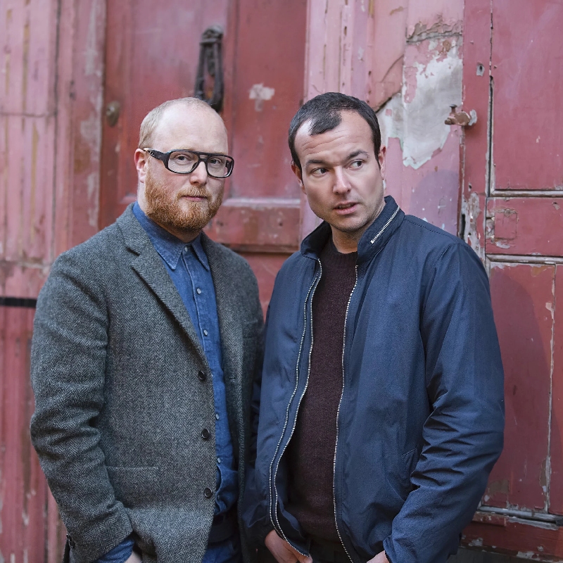 The Flight, two men standing in front of a rusty red door