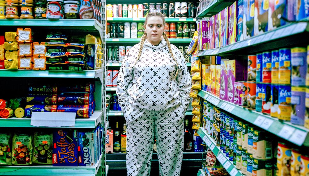 A woman in a Louis Vuitton tracksuit, standing in a supermarket