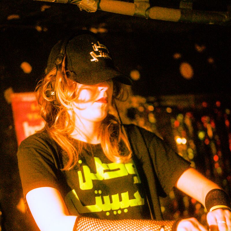 A person DJing wearing a cap and fishnet fingerless gloves