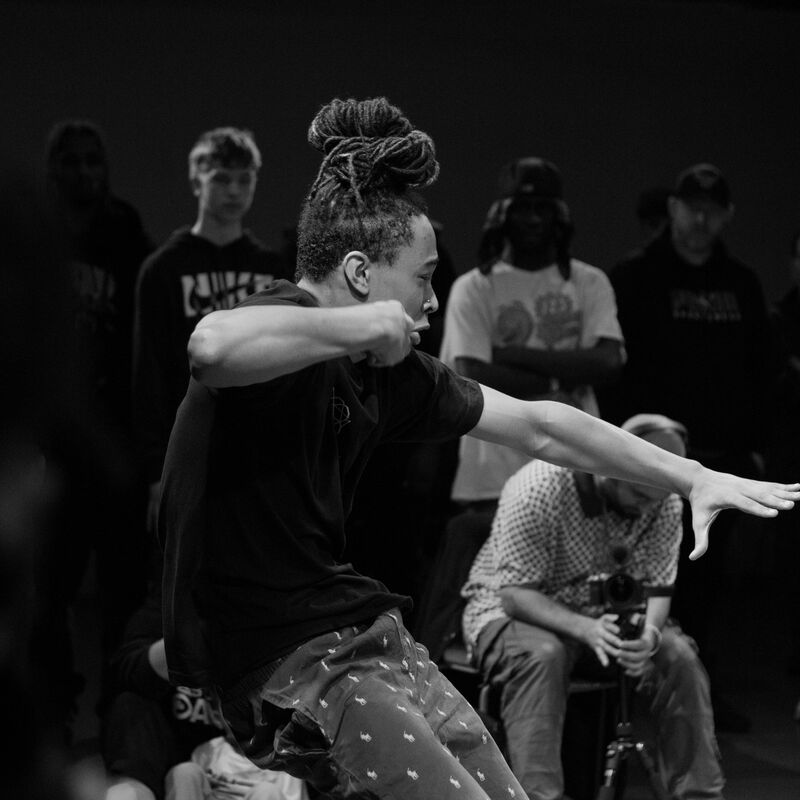 A dancer mid-move, surrounded by an audience