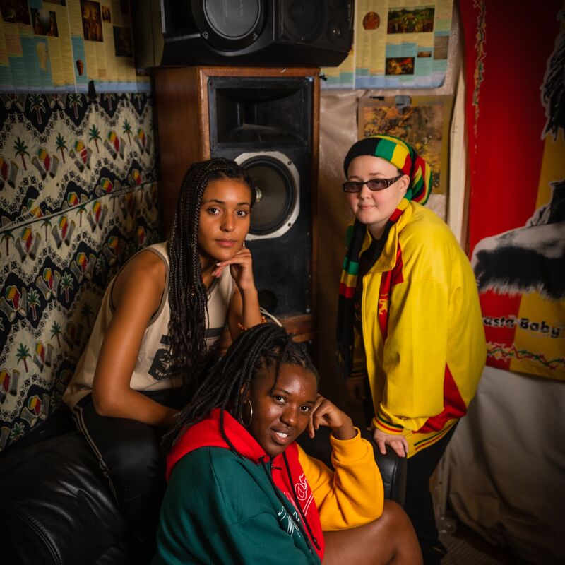 Three women sat in a room in front of a large sound system