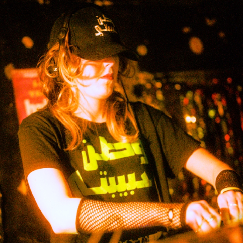 A person DJing, wearing a cap and fishnet fingerless gloves