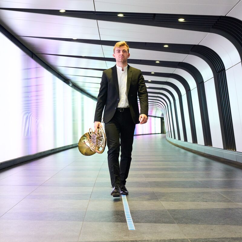 French Horn player Ben Goldscheider walks through a tunnel