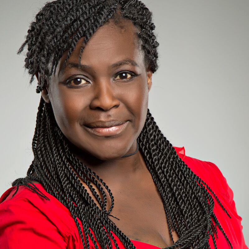 Headshot of Dr Maggie Aderin-Pocock in a red shirt looking directly into camera.